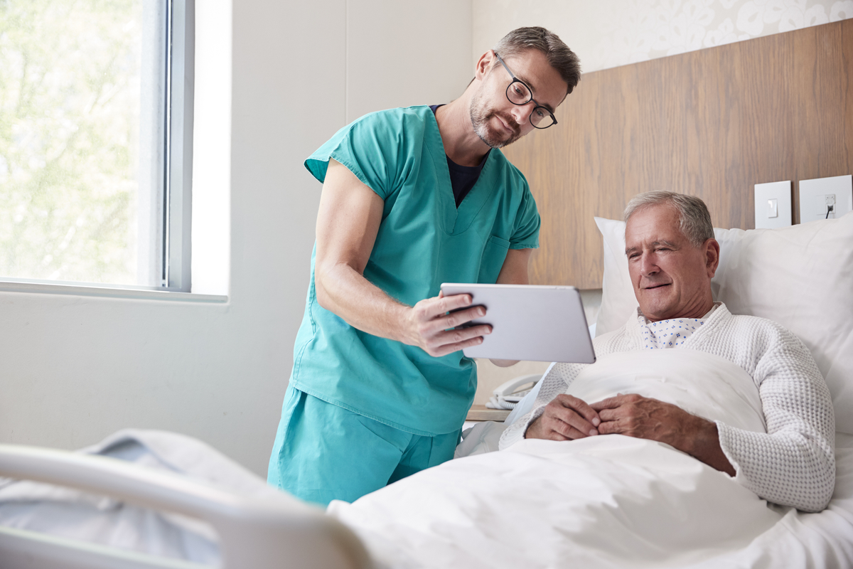 Hospital Care Image Surgeon With Digital Tablet Visiting Senior Male Patient In Hospital Bed In Geriatric Unit