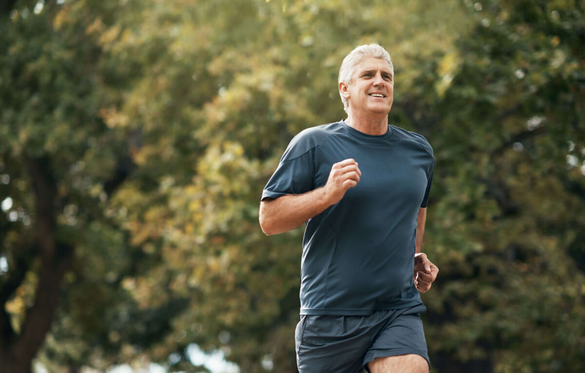 A fit older man goes running in a park.